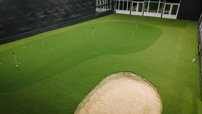 Golfa treniņu laukums telpās ar mākslīgo zāli, ripināšanas bedrītēm un smilšu zonu